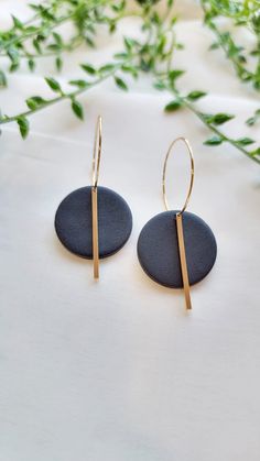 the gold hoop earrings are made with black stone and brass bar detailing, on a white background