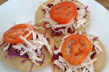 three tortillas with shredded cheese and tomatoes on them sitting on a white plate