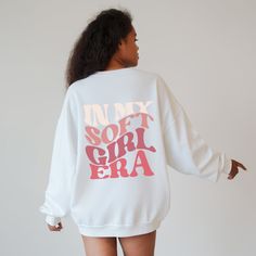 "Our retro In My Soft Girl Era Sweatshirt is designed to capture the essence of the soft girl aesthetic and add a touch of whimsy to your wardrobe. With its adorable smiley design in pink text and the phrase \"In My Soft Girl Era\" elegantly placed on the back, this sweatshirt is perfect for women who want to embrace or continue living their best soft life Ideal for any situation, a unisex heavy blend crewneck sweatshirt is pure comfort. These garments are made from polyester and cotton. This combination helps designs come out looking fresh and beautiful. The collar is ribbed knit, so it retains its shape even after washing. There are no itchy side seams on these sweaters.  - 50% cotton, 50% polyester - Medium-heavy fabric (8.0 oz/yd² (271.25 g/m - Loose fit - Sewn-in label - Runs true to Oversized Cute Sweater With Letter Print, Cute Oversized Letter Print Sweater, Cute Sweatshirt With Text Print For Streetwear, Cute Sweatshirt With Text Print And Long Sleeves, Cute Oversized Slogan Sweatshirt, Cute Relaxed Fit Sweatshirt With Letter Print, Cute Long Sleeve Sweatshirt With Text Print, Cute Sweater With Letter Print For Loungewear, Cute Letter Print Sweater For Loungewear