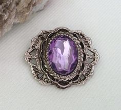 Exquisite vintage Victorian Revival silvertone and purple Paste stone brooch pin with locking clasp.  The metal on this pin feels very solid and the paste stone appears luminescent.  It is very stunning and unique.  In very nice condition.  Thanks for looking. Vintage Silver Brooch With Gemstone, Vintage Silver Gemstone Brooch, Vintage Purple Oval Brooch, Victorian Revival, Vintage Victorian, Brooch Pin, Brooches, Beauty Book, Silver Tone