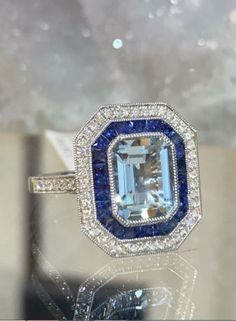 a fancy ring with an aqua and white topazte surrounded by blue sapphires