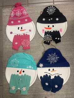 four snowmen wearing hats and mittens on paper plates