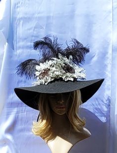 Black and white flowers with jeweled center surrounded by black plume feathers arranged atop a black hat base with wide purple satin ribbon as hat band. Step out this Spring wearing this lovely large flower hat. Measures 14" x 14" x 8". Black High Crown Hat For Formal Occasions, Black High Crown Costume Hat For Formal Occasions, Formal Black High Crown Costume Hat, Feather Trim Top Hat For Royal Ascot Evening, Top Hat With Feather Trim For Royal Ascot Evening, Black Costume Hats For Royal Ascot Party, Evening Top Hat With Feather Trim For Royal Ascot, Elegant Top Hat For Kentucky Derby Costume Party, Elegant Black Top Hat With High Crown