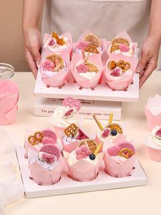 a table topped with pink cupcakes and pretzels