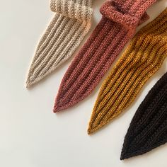 four knitted ties are lined up on a white surface