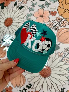 The KC Teal Soccer Ball Trucker Hat is a stylish addition to your wardrobe. Featuring a vibrant Red heart, KC, Soccer Ball makes this hat is perfect for adding a pop of color to any outfit. Made with high-quality materials, it provides both comfort and durability, making it a must-have for any fashion-forward individual. Details: Adult Size Adjustable Fit One Size Fits Most Trucker Hat Mesh Back Lightweight 100% Polyester Sports Trucker Hat, Hat Bar, Patch Hats, Personalized Hats, Hat Ideas, Soccer Fans, 12th Birthday, Bar Ideas, Soccer Team