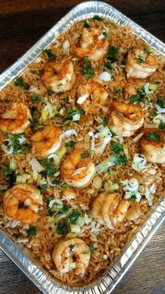 a pan filled with shrimp and rice on top of a wooden table