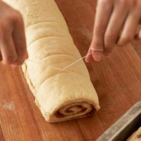 a person is holding a piece of bread on a cutting board