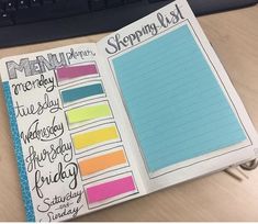 an open planner book sitting on top of a wooden desk next to a computer keyboard