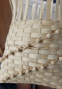 a woven basket sitting on top of a wooden chair next to a person's legs