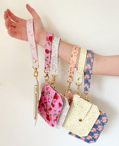 a hand is holding several small purses with different colors and designs on each one