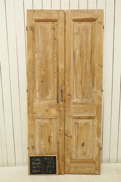 an old pair of wooden doors with chalkboard on the bottom and bottom, in front of a white wall