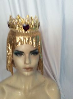 Gold metal crown, with ruby crystal hearts, on a gold metal mesh. INside a buckram base holds an adjustable strap for a good fit, one size fits all. High Crown Gold Headpiece For Festival, Gold High Crown Headpiece For Festivals, Gold Crown With Pinched Shape For Festivals, Gold Teardrop Crown For Festival, Elegant High Crown Gold Crown, Gold Crown Design Headpiece With Pinched Crown, Gold Regal Headpiece With Tall Crown, Gold Structured Crown Headpiece For Festival, Regal Gold Crown With Structured Shape