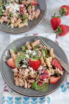 two plates filled with pasta salad and strawberries