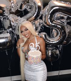 a woman standing in front of balloons with a cake on her chest and the number 50 written on it