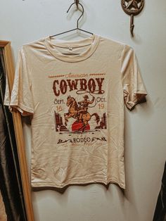 Yeehaw, this American Cowboy Rodeo Graphic Tee is the real deal! Featuring a bold graphic print of a rodeo cowboy, this tee is perfect for rodeo enthusiasts and anyone looking to add a touch of cowboy flair to their wardrobe. Giddy up and grab one now! Western Shopping, American Cowboy, Western Clothes, Cowboy Rodeo, Cowboy Shirt, Western Style Outfits, Rodeo Cowboy, 2024 Style, Cowboys Shirt