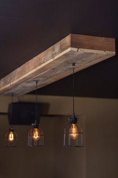 three light bulbs hanging from the ceiling in a room with dark walls and wooden beams