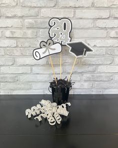 graduation cake topper and decorations on a black table with brick wall in the background