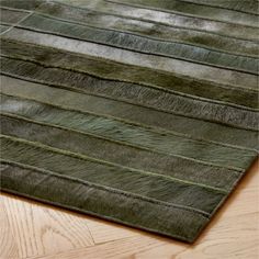 an area rug with green and grey stripes on the top, along with wood flooring