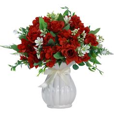 a white vase filled with red flowers and greenery