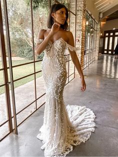 a woman in a wedding dress posing for the camera with her hand on her hip