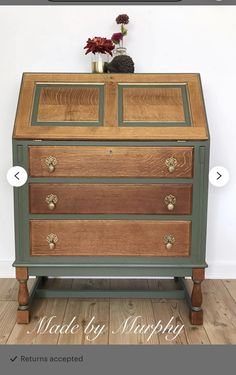 an old dresser has been painted with green and gold paint on the top, along with flowers in a vase