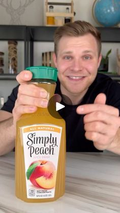 a man is holding up a bottle of simply peach juice and pointing to the camera