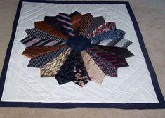 a quilted table top with many different ties laid out in the shape of a flower