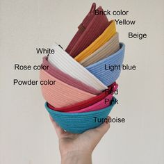 a hand holding a stack of colorful knitted headbands with the names labelled