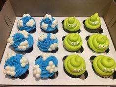 cupcakes with green and blue frosting are in a box on the table