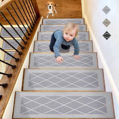 a toddler crawling down the stairs in front of a stair mat with a dog on it