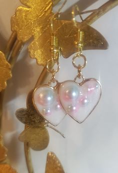 These earrings are a fun, cute addition to any outfit! They were made using a metal open bezel, UV resin, and decorate iridescent half pearls. -Each item is handmade -Any resin may contain small bubbles, which is normal for this type of medium -All sales are final, no returns, refunds, or exchanges. But if you have any questions regarding your order feel free to message me! Pink Enamel Earrings For Party, Iridescent Pearl Drop Earrings As Gift, Iridescent Pearl Drop Earrings For Gift, Handmade Iridescent Metal Earrings, White Heart-shaped Pearl Charm Earrings, Trendy Pearl Drop Earrings As Gift, White Enamel Jewelry For Party, Whimsical Silver Resin Jewelry, Cute Hypoallergenic Party Jewelry