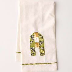 two towels with an elephant embroidered on one side and green, white, and yellow designs on the other