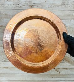 a large metal bowl sitting on top of a wooden table next to a black glove