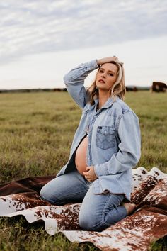 a pregnant woman sitting on top of a blanket