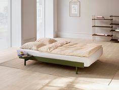 a bed sitting on top of a hard wood floor next to a book shelf filled with books