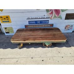 a wooden table sitting on wheels in front of a building