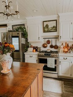 a kitchen with white cabinets and wooden counter tops, an island in the middle has flowers on it