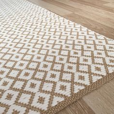 an area rug with white and brown designs on top of wood flooring in a living room