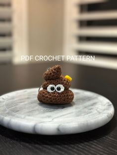 a crocheted brown bird sitting on top of a white marble plate with eyes