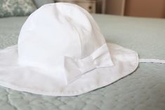 a white hat with a bow sits on a bed