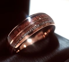 a wedding band with wood inlays is shown on top of a black cloth