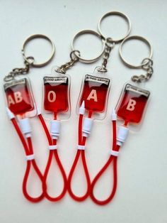 four red and white medical key chains with the letters ab on them are attached to each other