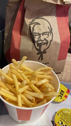 a close up of a bowl of french fries on a table with a bag in the background