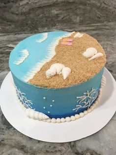 a blue and white cake with sand on top