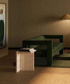 a green couch sitting next to a table on top of a hard wood floor in front of a painting