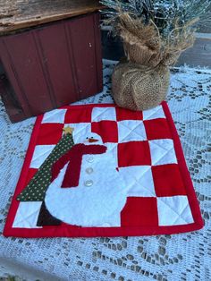 a red and white quilt with a santa clause on it next to a potted plant