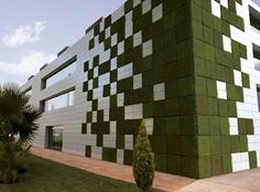 the building is made out of green and white tiles on it's side, with trees in front