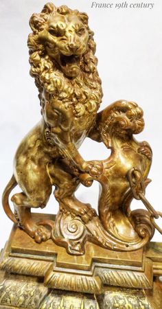 a golden lion statue sitting on top of a wooden base