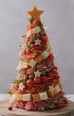 a christmas tree made out of fruits and cheeses on a cutting board with an orange star